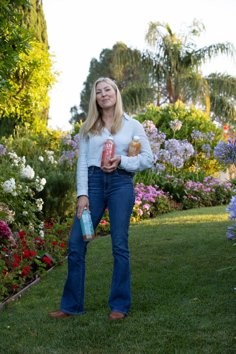 Founder holding bottled drinks in a garden setting commercial branding photography san diego by Siobhan Gazur Photography