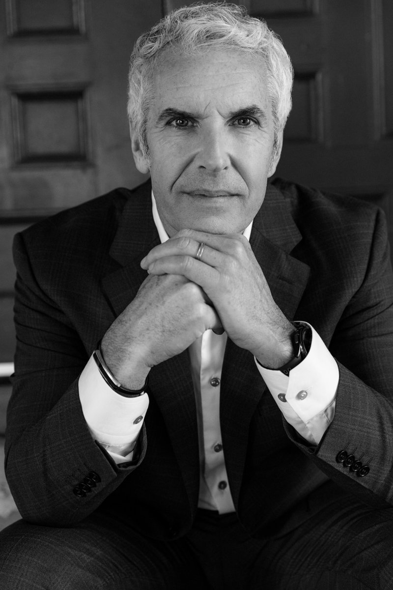 Black-and-white executive branding portrait of a business man seated with hands folded san diego branding photography by Siobhan Gazur Photography